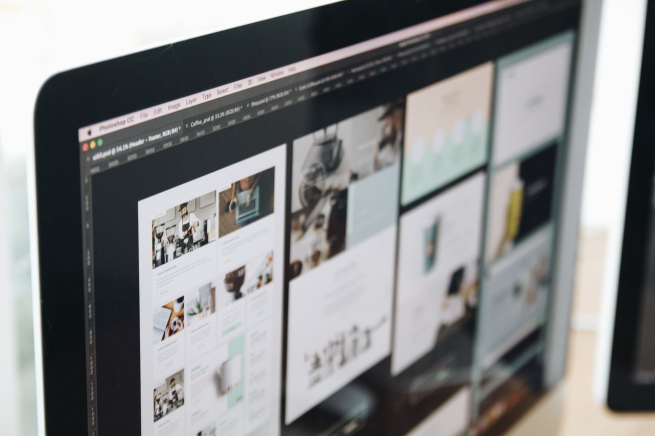 Un écran d’ordinateur moderne affichant un travail de web design, avec des visuels créatifs dans un espace de travail.